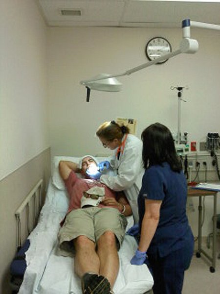 0609121411.jpg - Here the Doc is injecting him with some pain killer.  Real fishermen don't need pain killers.  They merely push the hook through the skin, chop off the barb and back the hook out.
